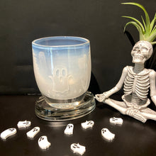 Load image into Gallery viewer, And etched ghost botive is on display with small white acrylic ghost table scatter. Sitting next to the votive is a skeleton sculpture in a yoga pose with an air plant as hair.
